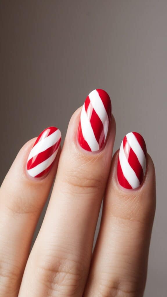 Close-up of a hand with red and white candy cane striped nail art on fingernails against a plain background.